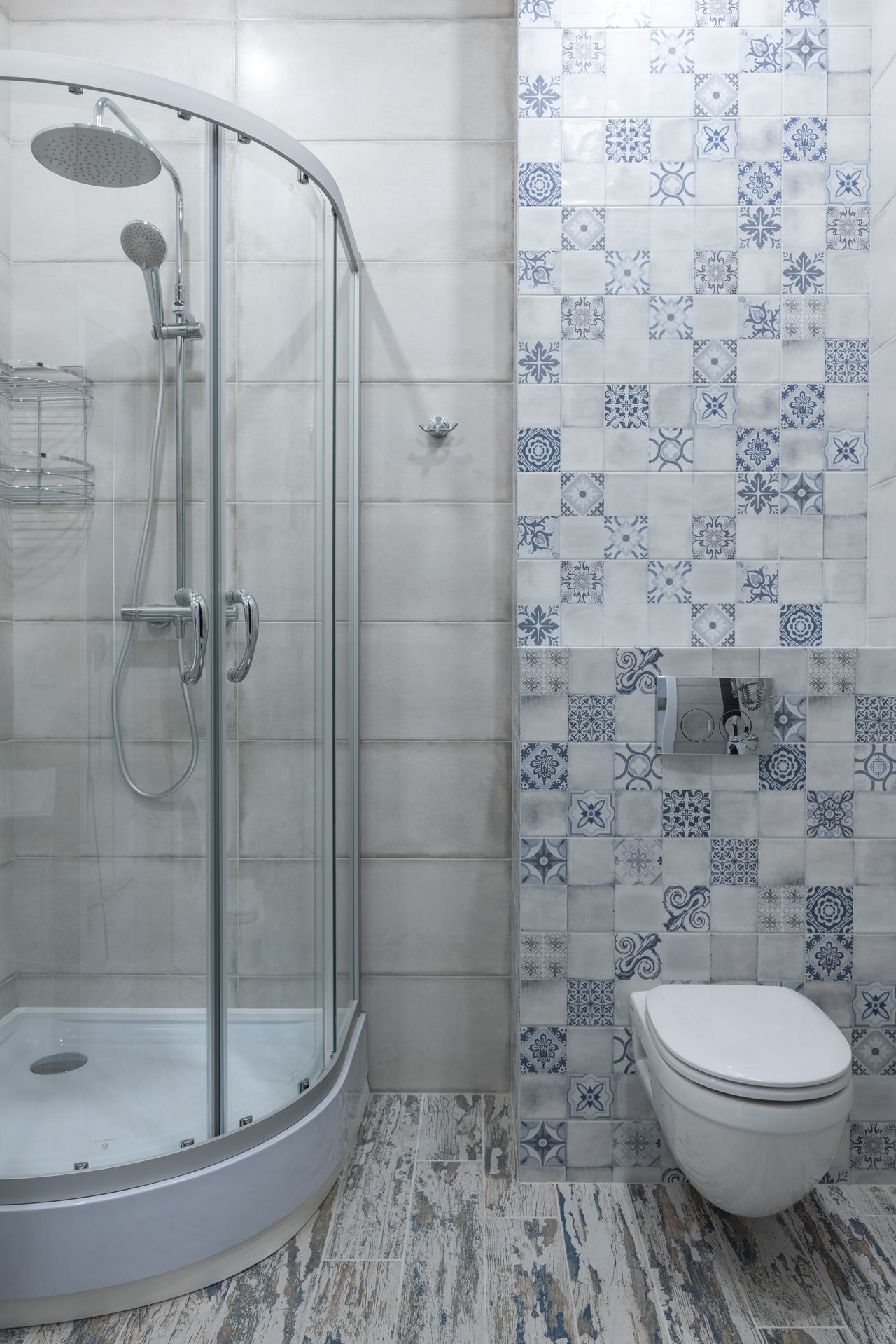 Corner shower beside a wall of blue and white patterned patchwork tiles