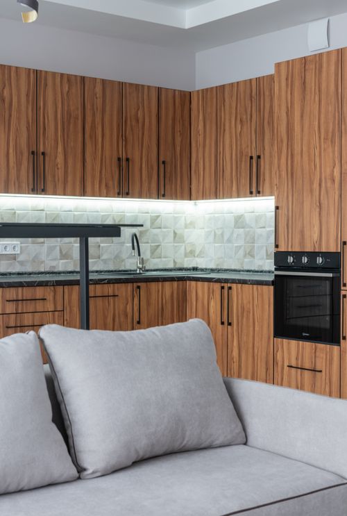 Free Interior of modern kitchen counter with sink near modern black oven placed near bar counter and comfortable couch in stylish apartment Stock Photo