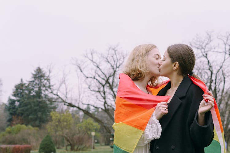 Same Sex Couple Kissing While Holding Gay Pride Flag