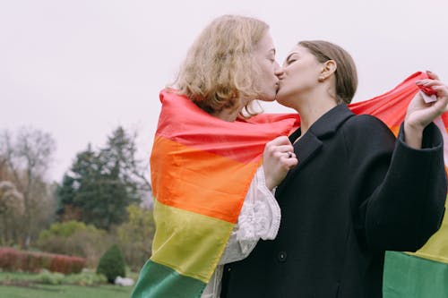 Couple Holding Gay Pride Flag Kissing