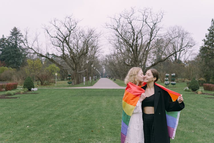 Couple Holding Together Gay Pride Flag Around Shoulders