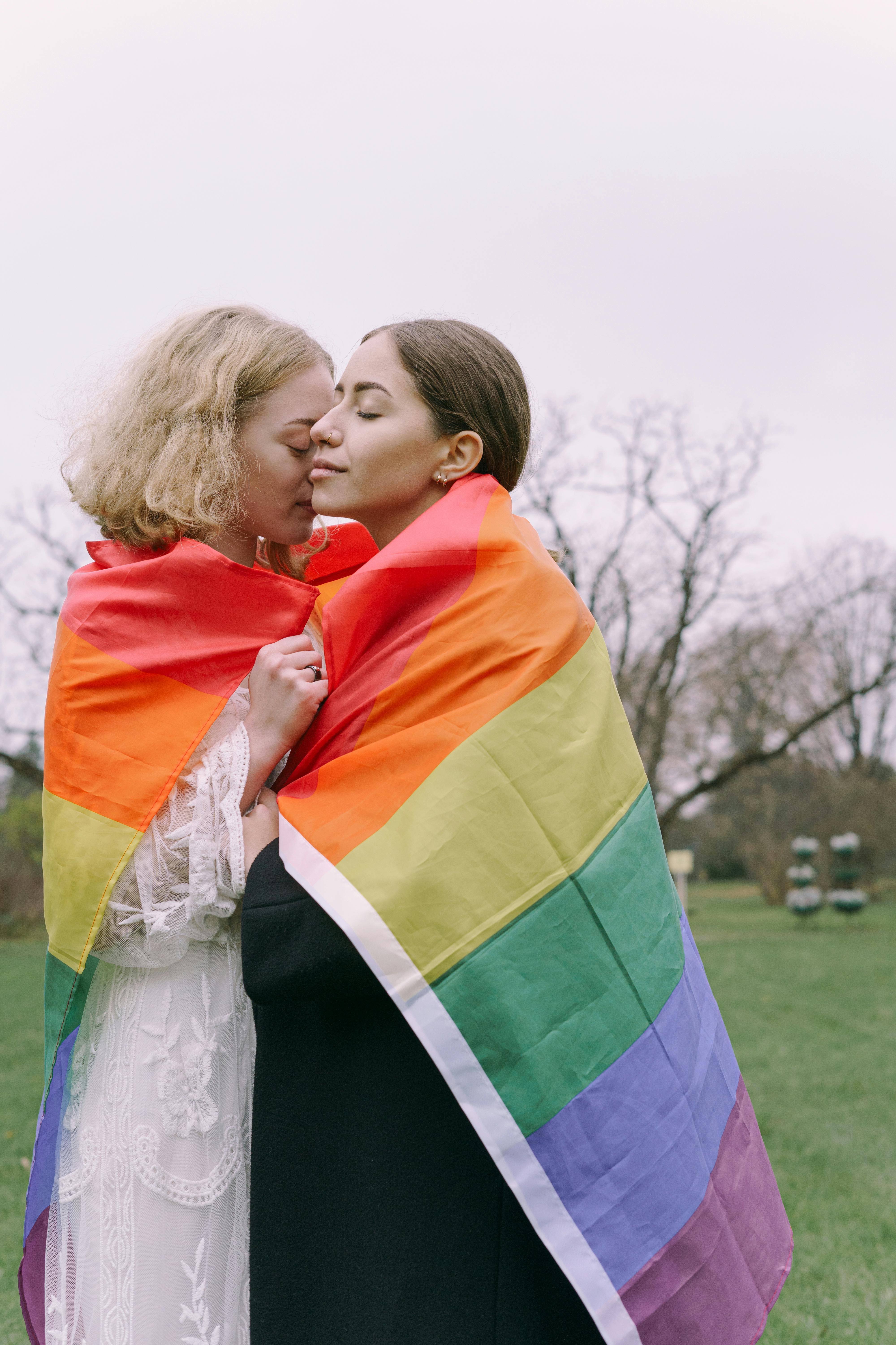 sweet couple with gay pride flag wrapped around their shoulders