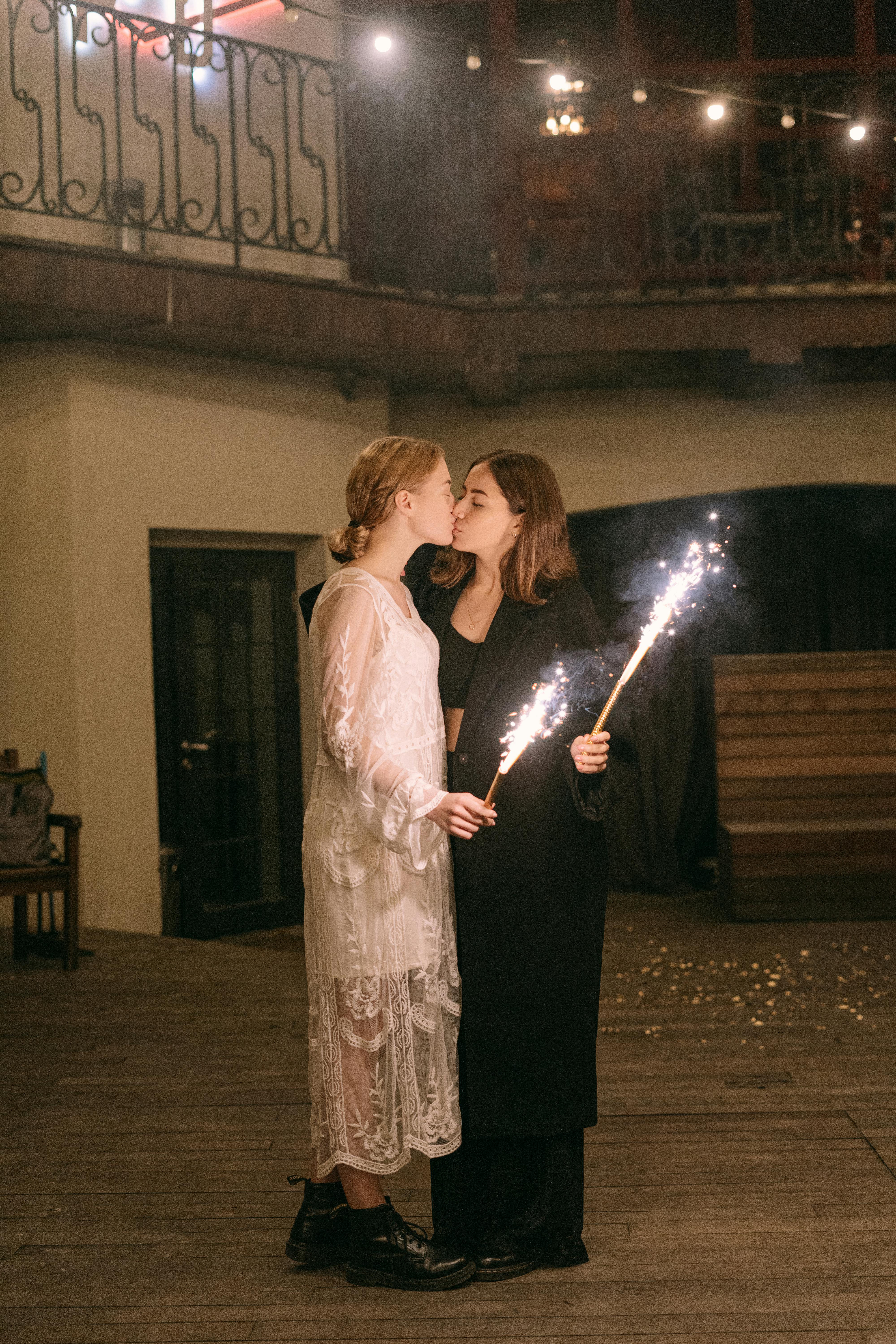 a same sex couple kissing each other while holding sparklers