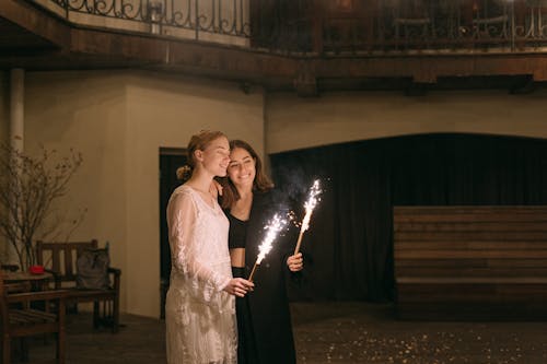 Two women enjoying an intimate moment with flashlers in an indoor setting, radiating happiness and warmth.