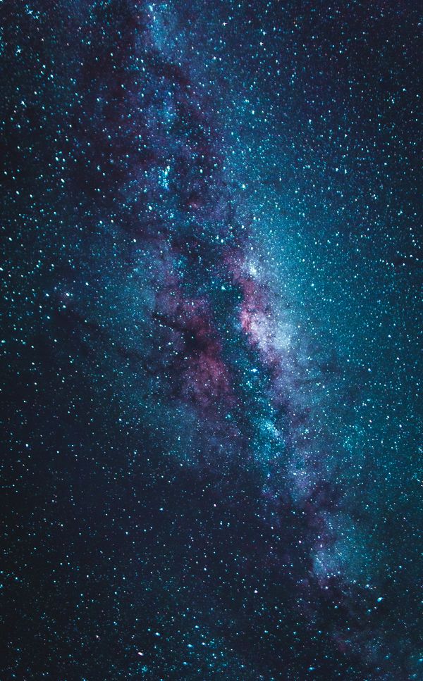 Vista vertical deslumbrante da galáxia Via Láctea em tons de azul e roxo sob um céu estrelado.