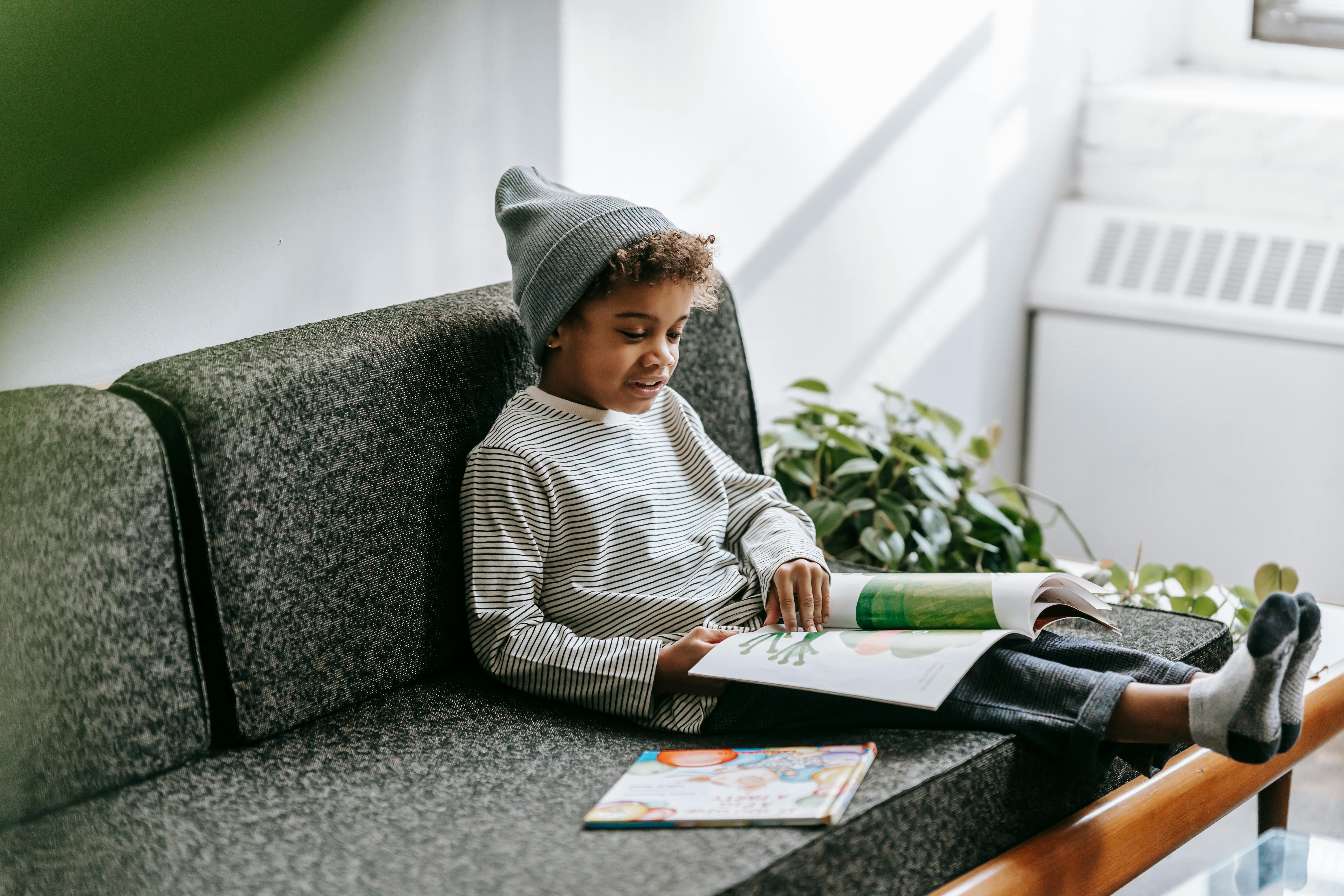 cute black boy in stylish outfit reading magazine