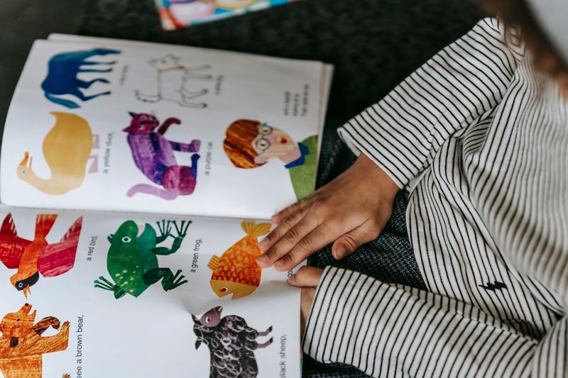 Close-up of a child's hands turning the pages of a colourful picture book