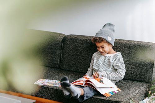 Free Full body of happy little African American boy smiling and watching pictures of fairytale in book Stock Photo
