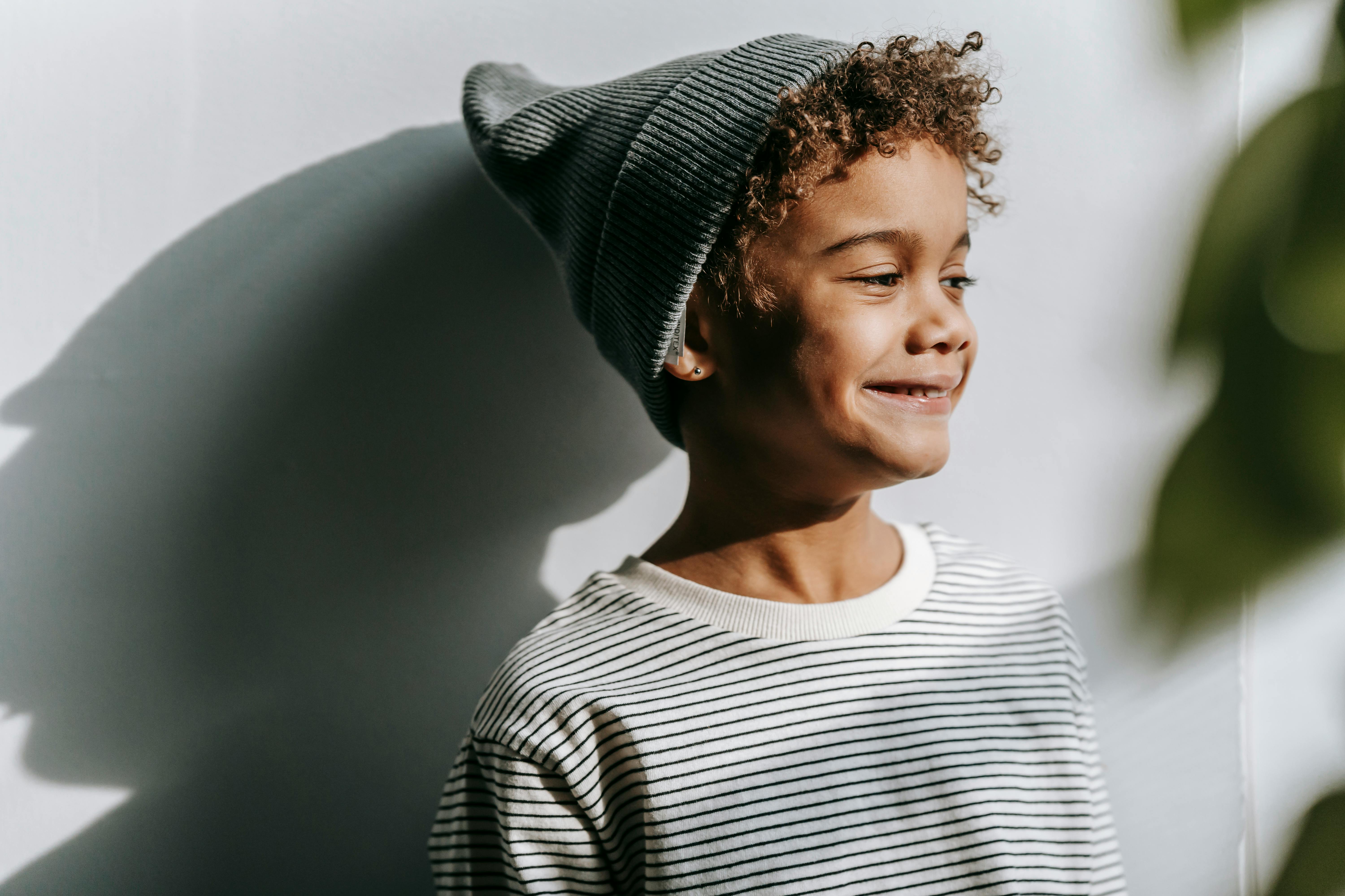 positive black boy smiling near wall