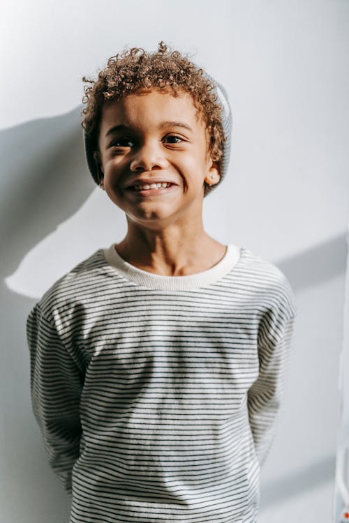 Carefree cute black boy in striped sweatshirt smiling