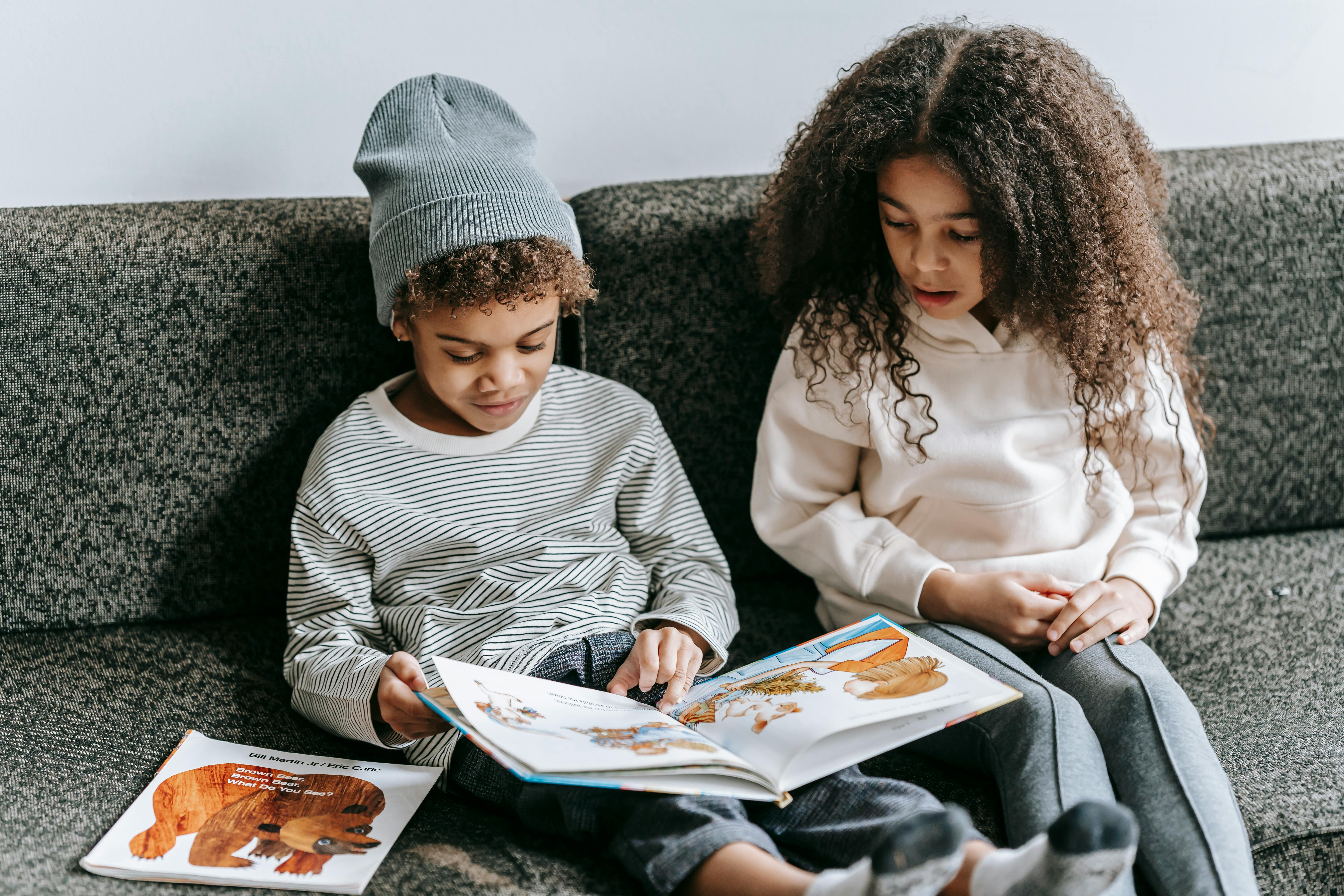 focused black boy and girl watching interesting book