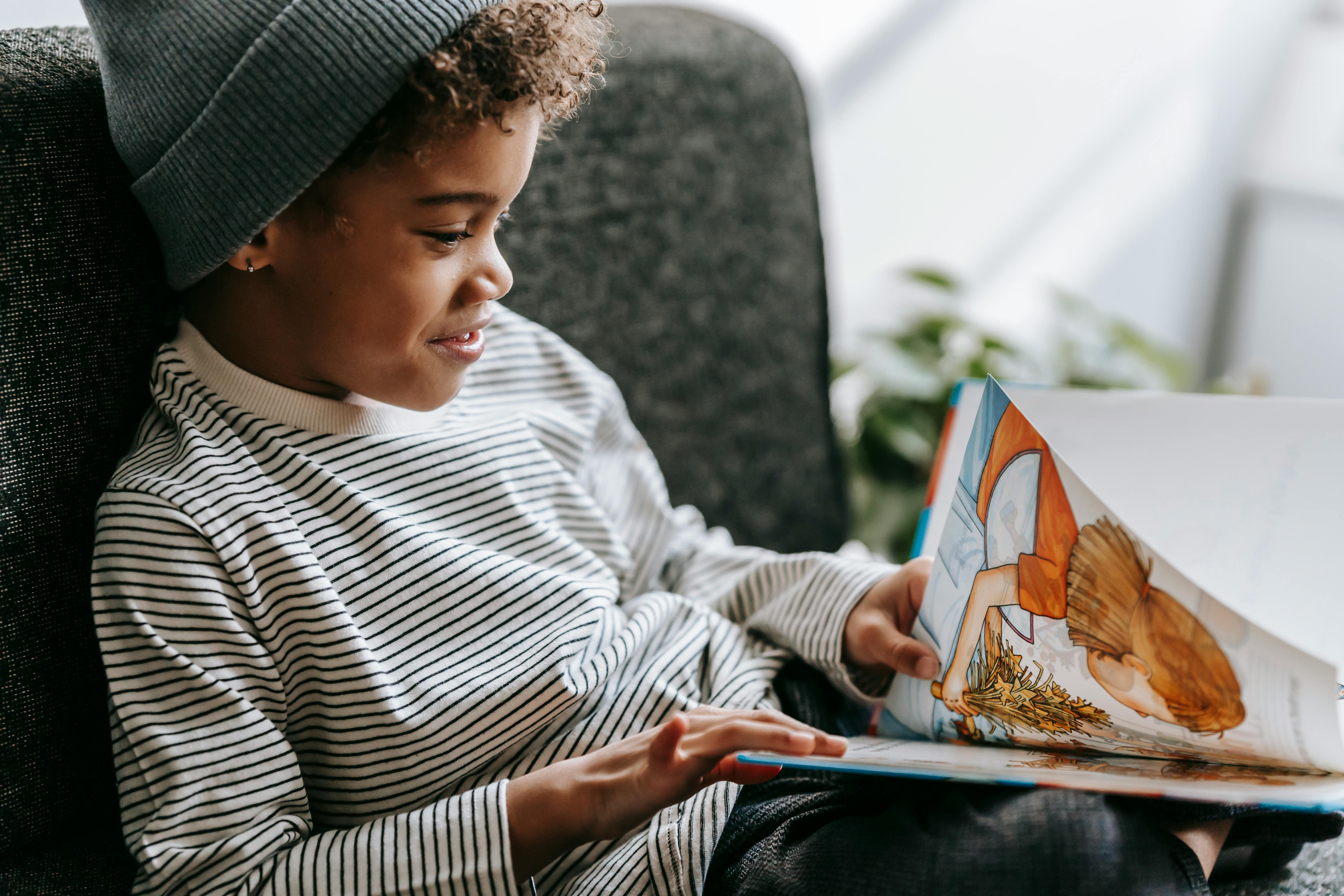 happy black boy reading fairytale with colorful pictures