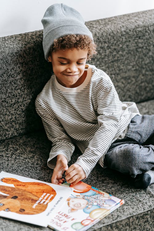 Free Cute happy black boy looking at pictures on books Stock Photo