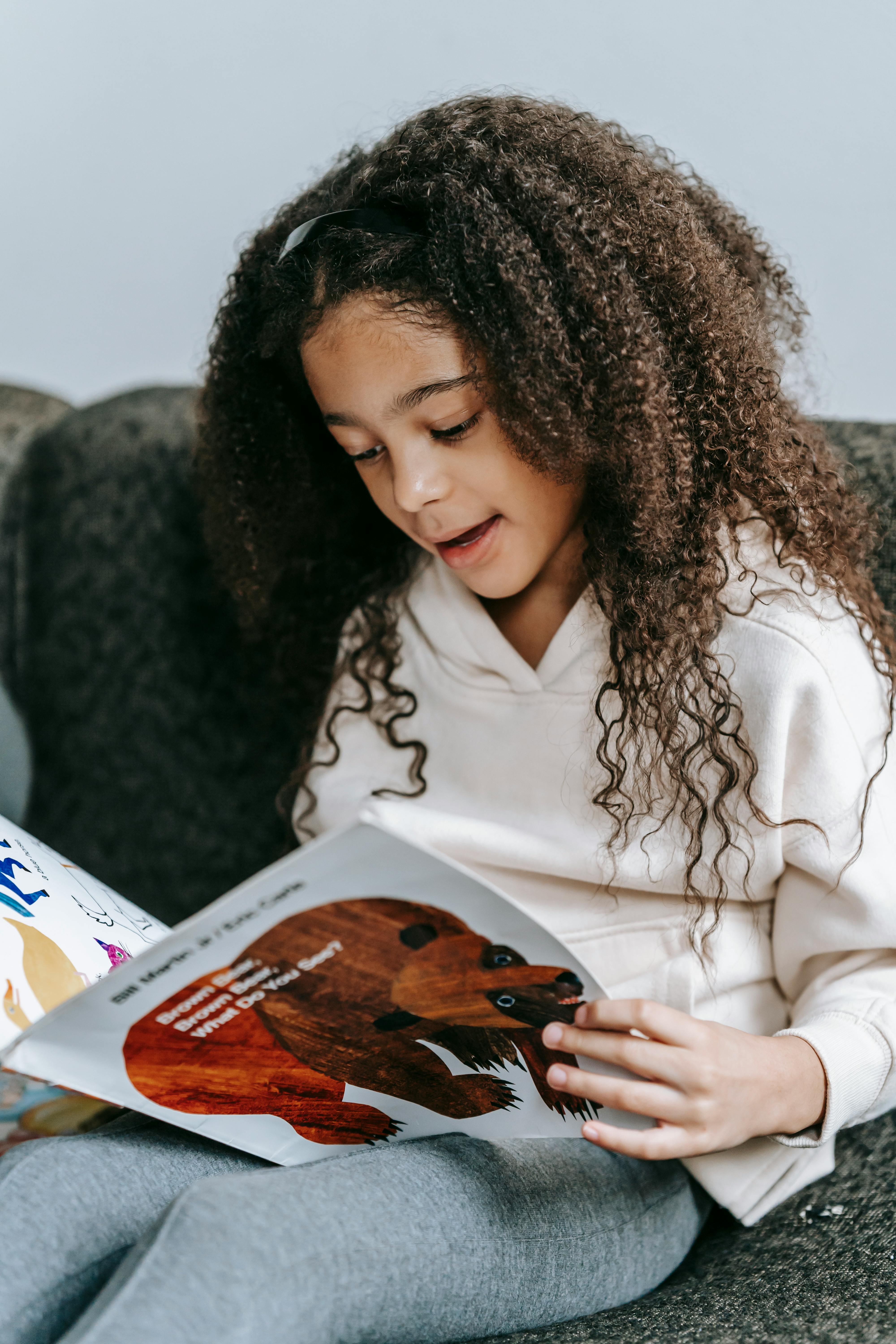 adorable smart black girl reading book with animals