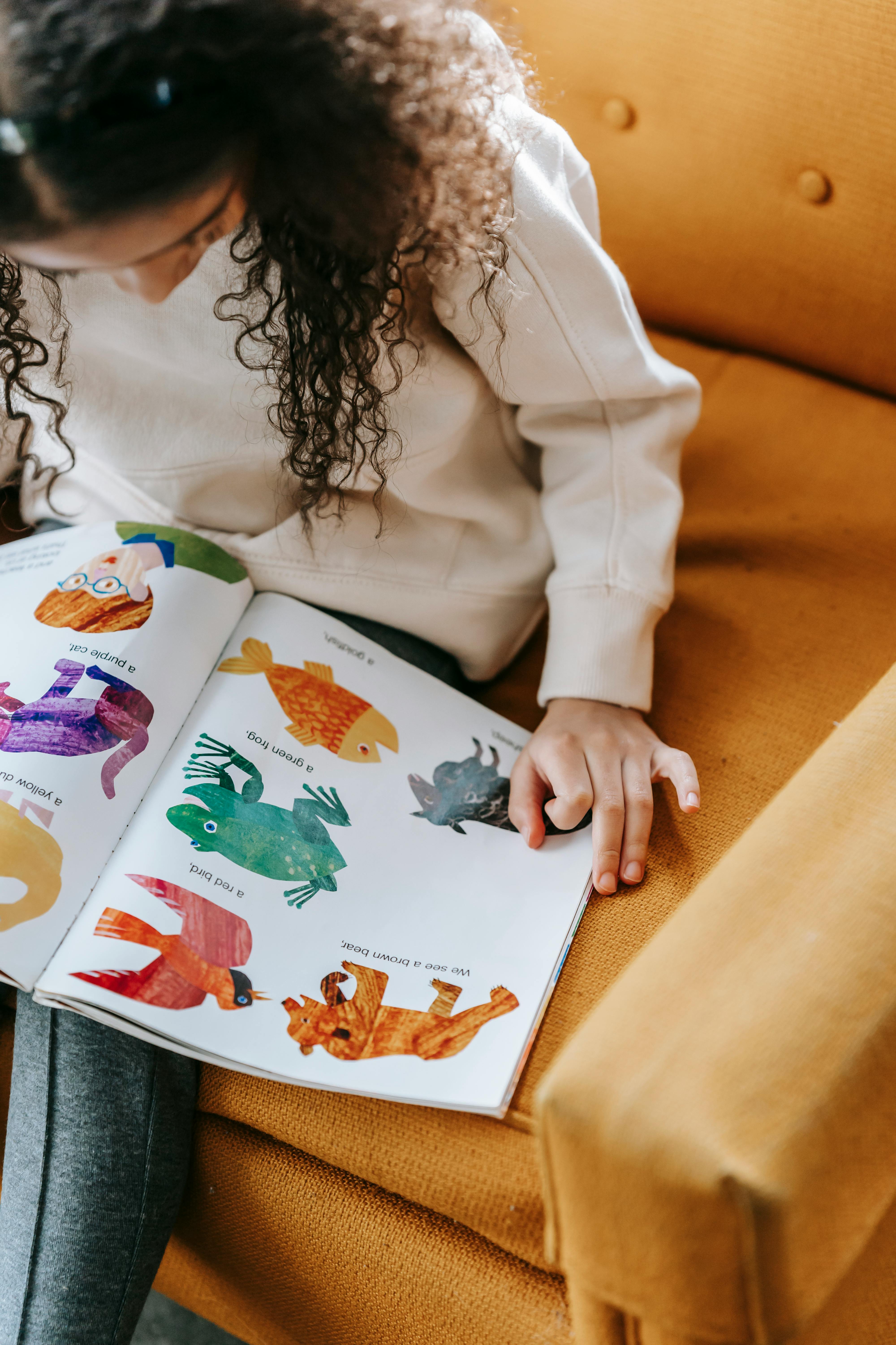 crop unrecognizable girl reading book on armchair