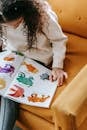 Crop unrecognizable girl reading book on armchair