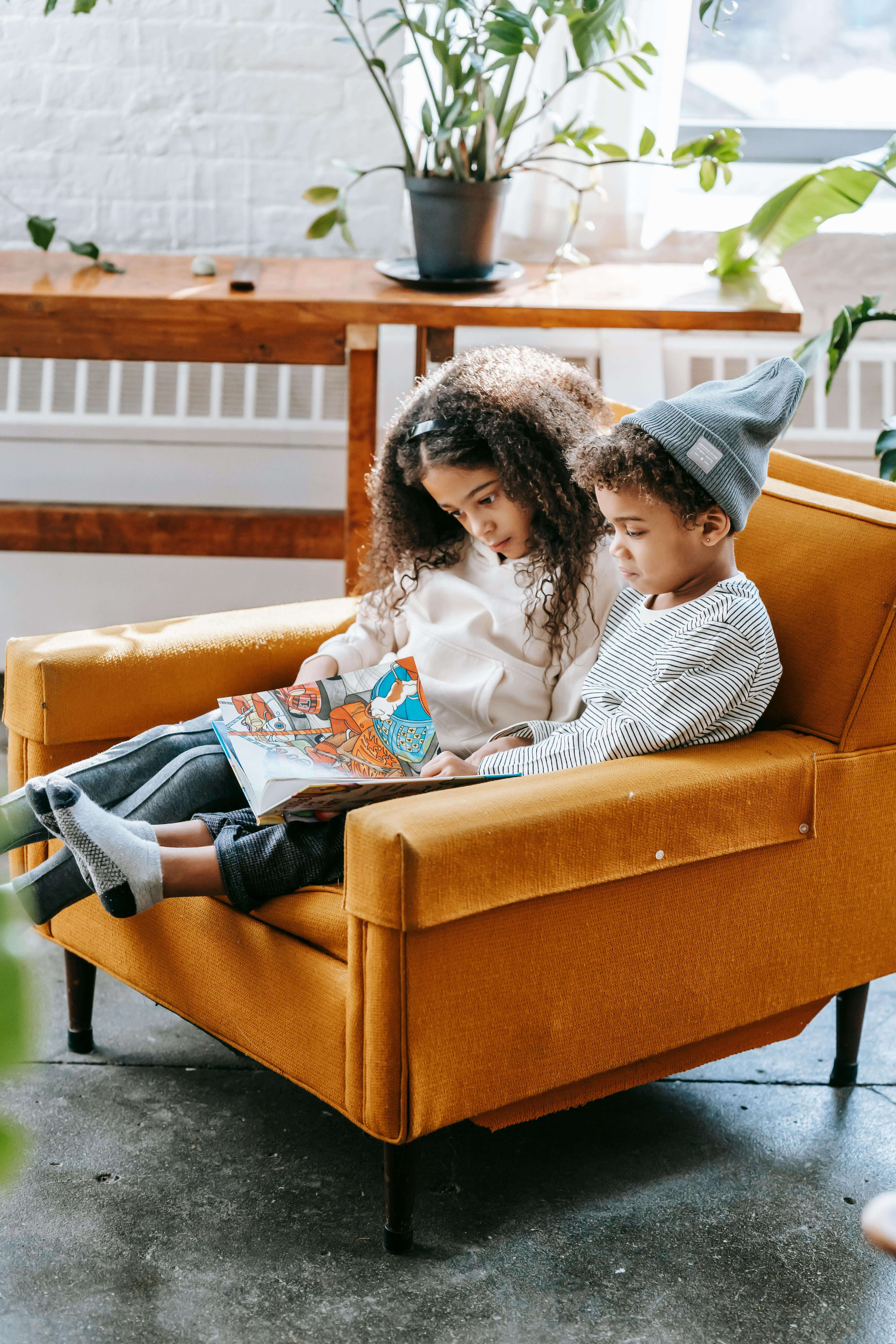 pensive black kids reading book on armchair