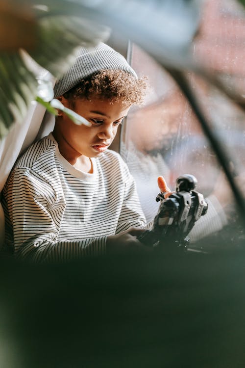 Thoughtful African American boy playing with toy at home