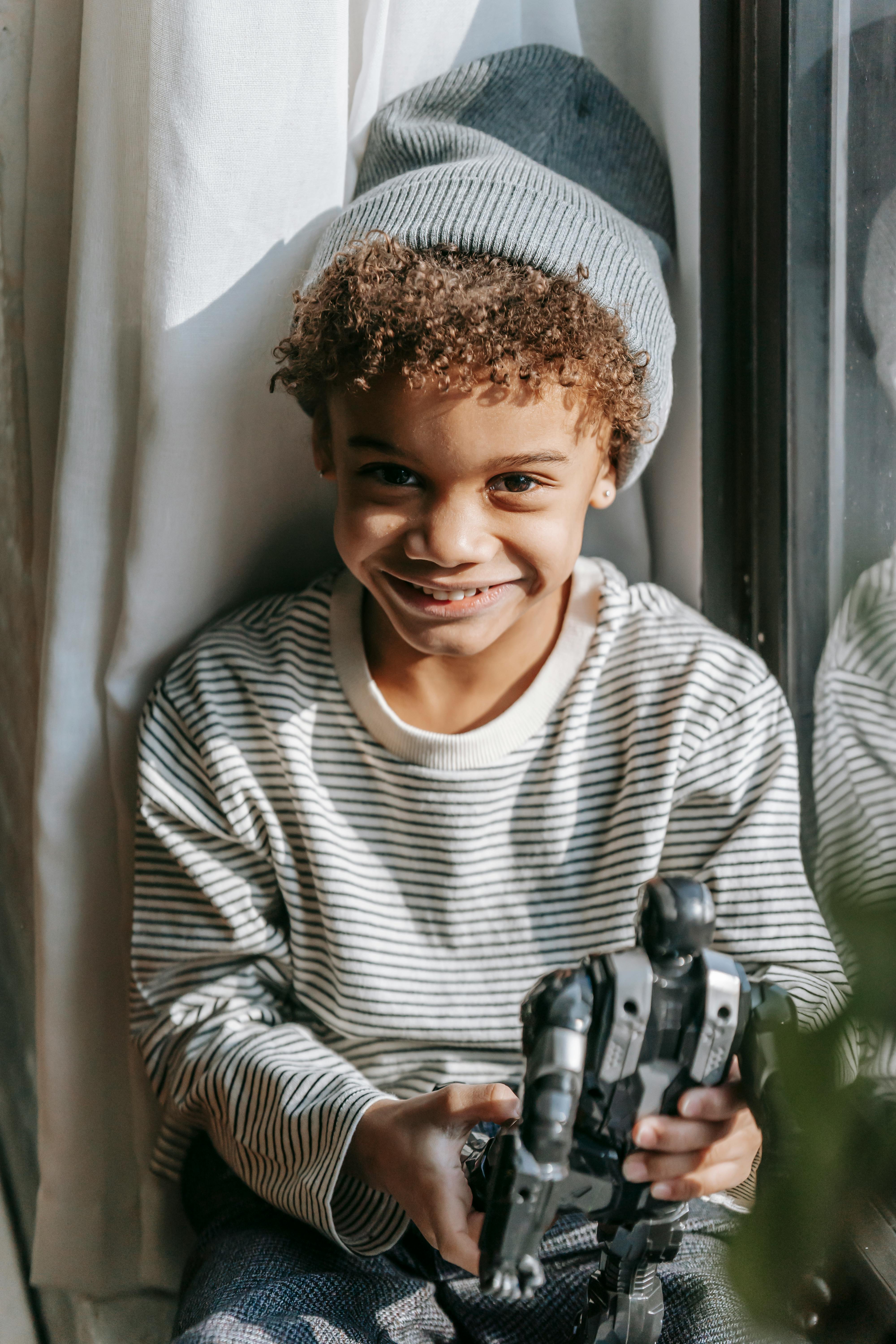 smiling black boy with robot toy near window