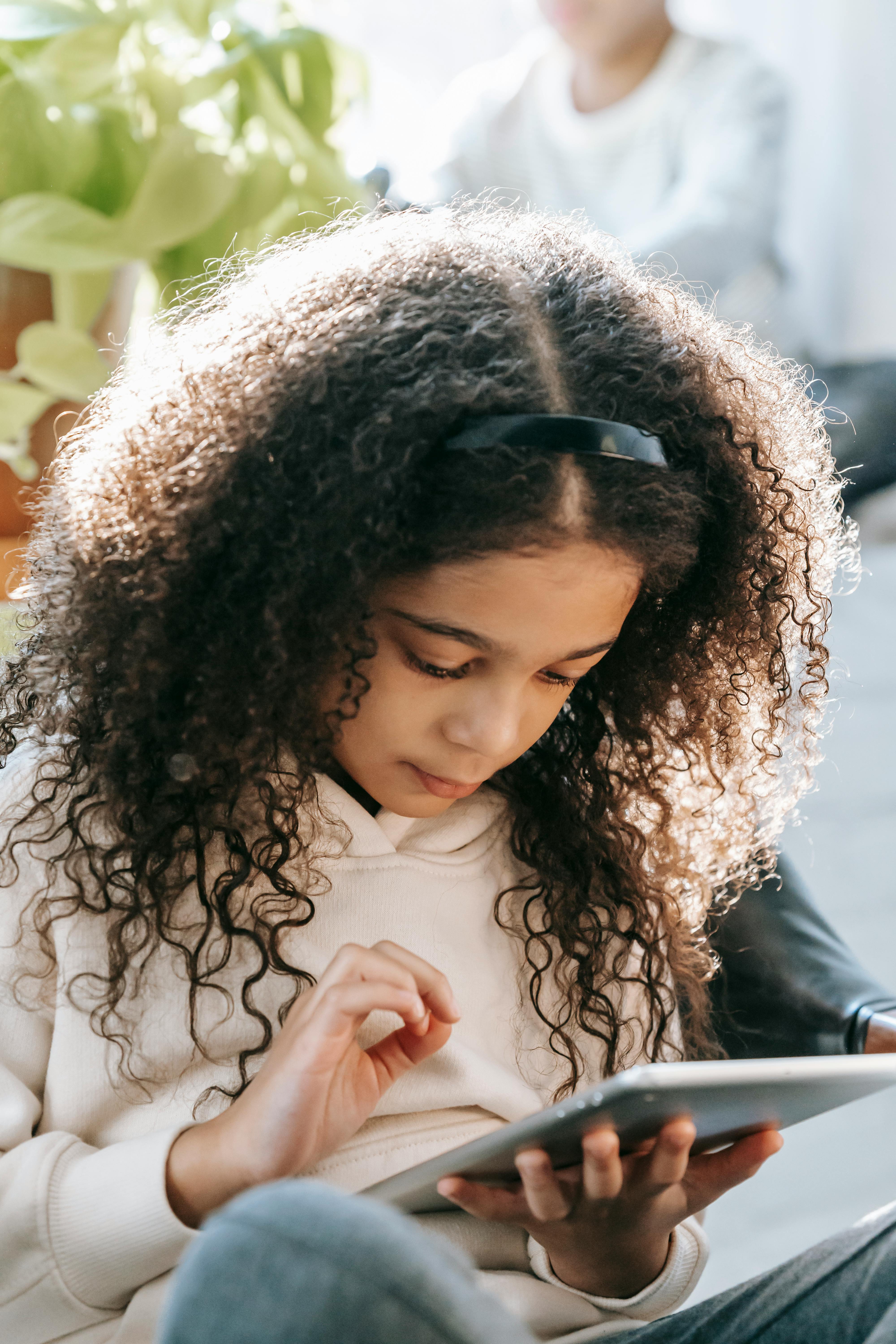 african american girl with tablet near brother on windowsill