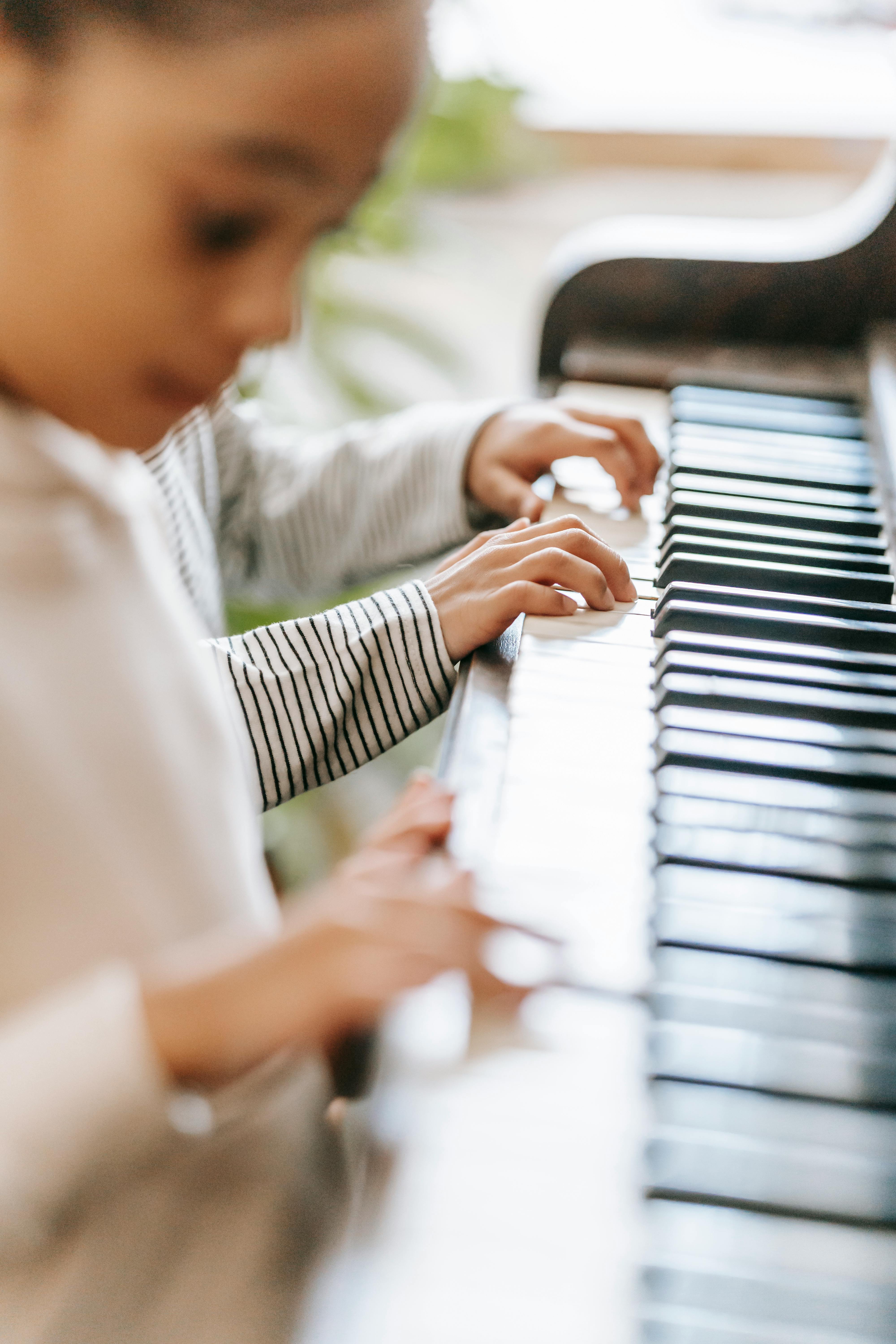 faceless ethnic children playing piano at home