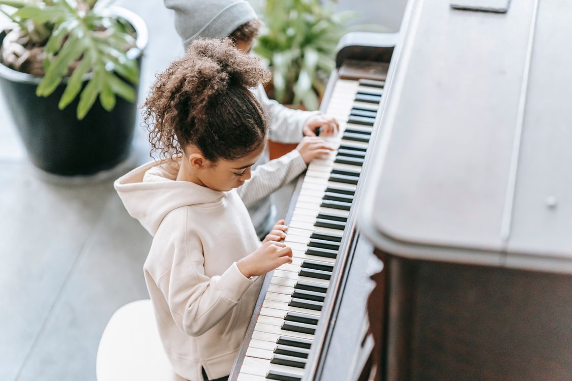 Des enfants jouent du piano dans une pièce lumineuse.
