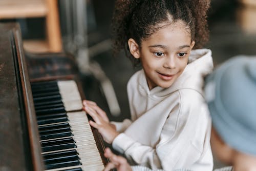 Gadis Tersenyum Berbaju Putih Lengan Panjang Bermain Piano