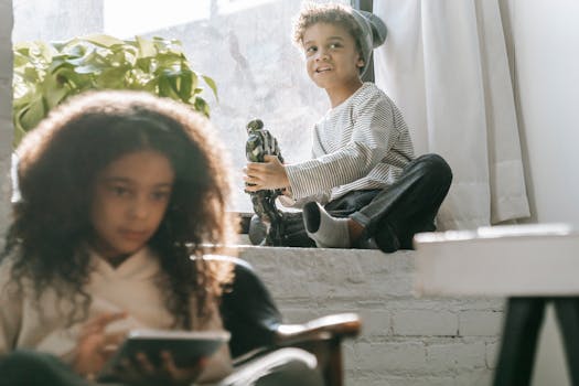 Two children spending quality time at home by a sunny window.