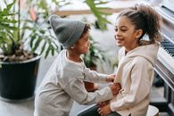 Positive black boy tickling girl near piano at home