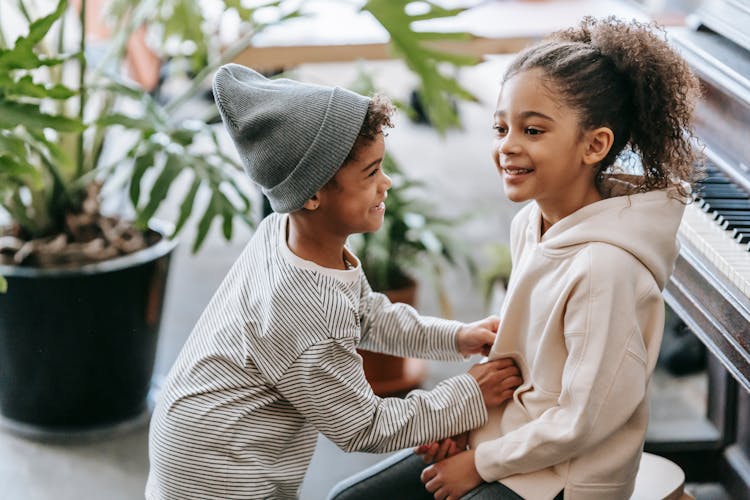 Positive Black Boy Tickling Girl Near Piano At Home