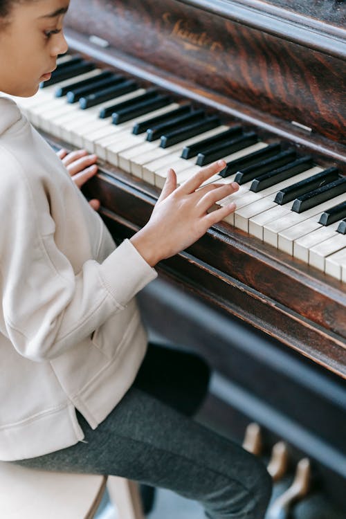 Faceless ethnic girl playing piano at home
