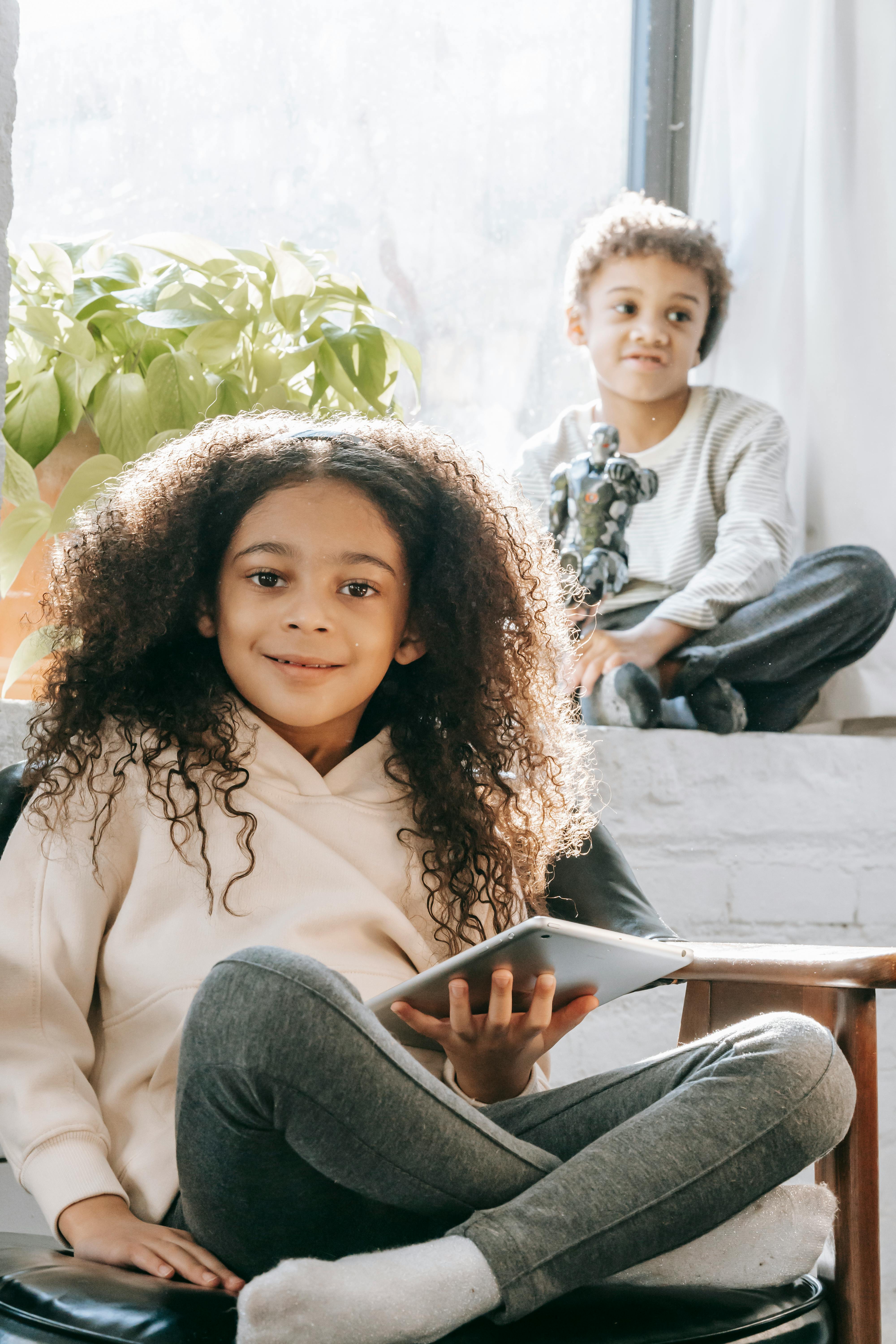 african american sister with tablet near brother with robot toy