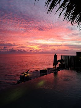 Mesmerizing sunset view over an infinity pool in the Maldives with pink skies.