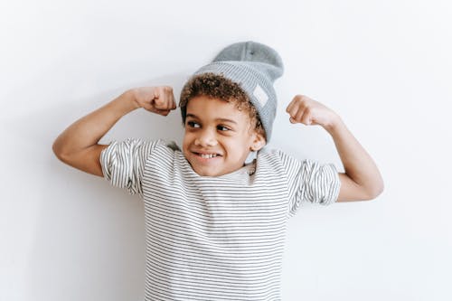 Cheerful black boy showing biceps