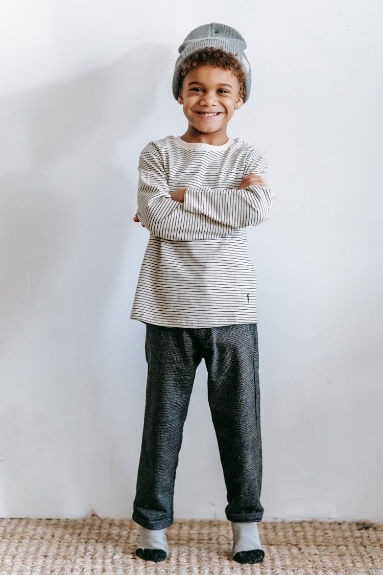 Cheerful Black Boy In Hat Standing Near Wall