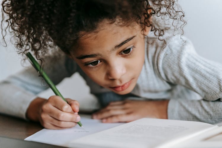 Focused Black Girl Writing On Paper