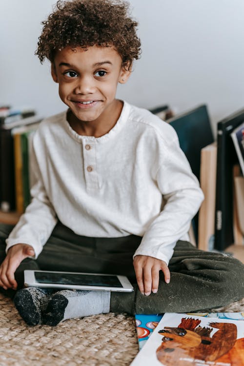 Cheerful black boy with tablet in room