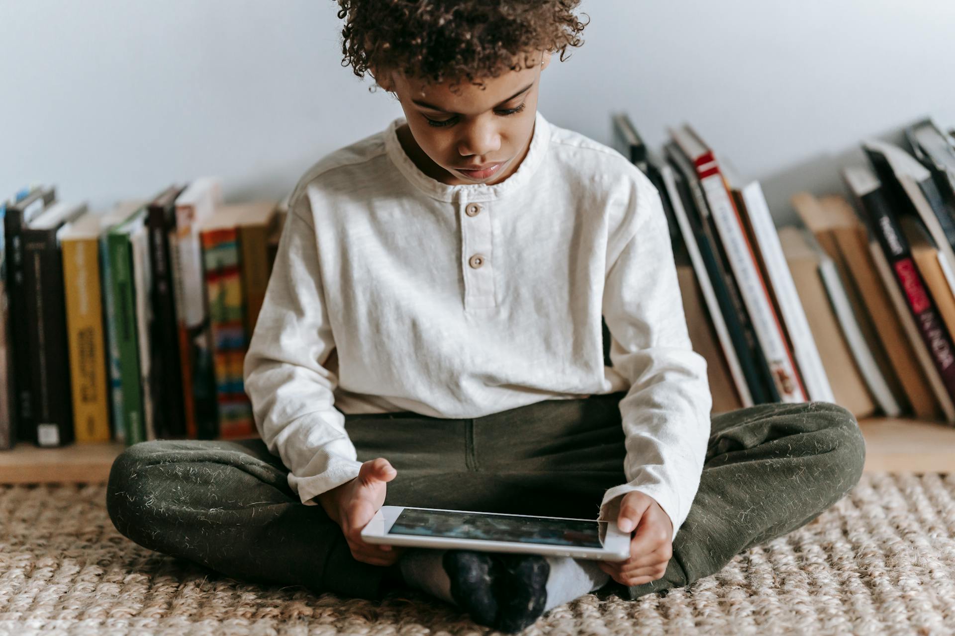 Crop black boy browsing tablet in room