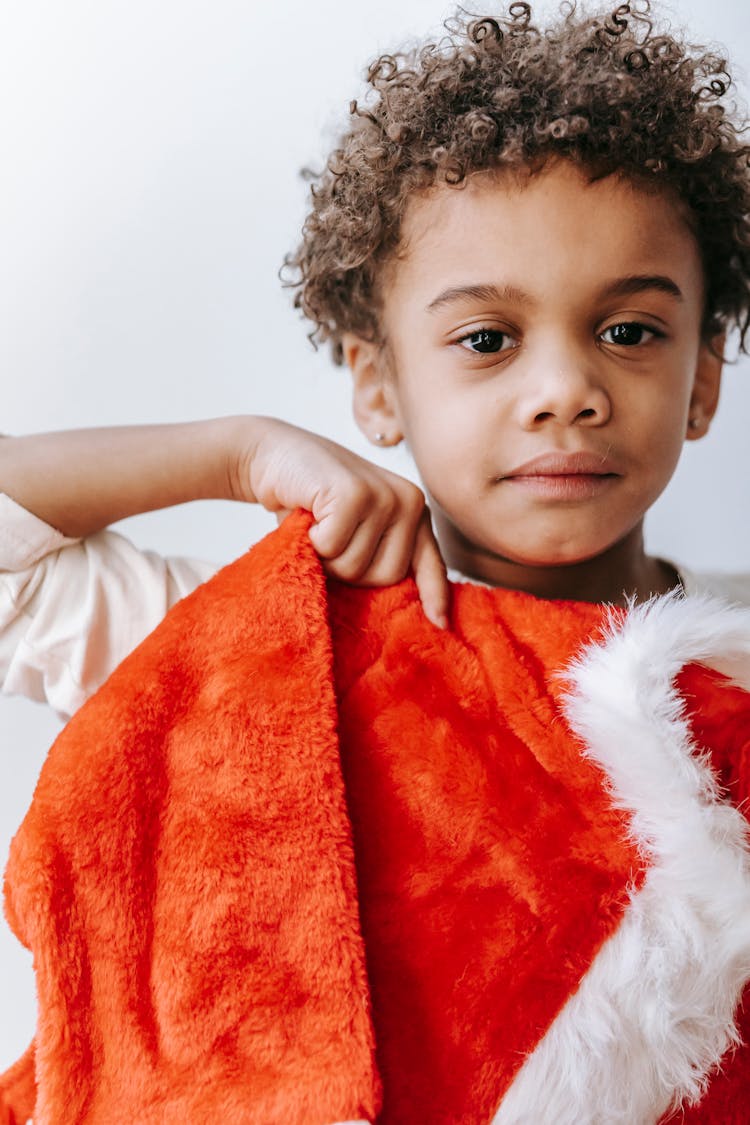 Calm Black Boy With Santa Claus Costume In Room