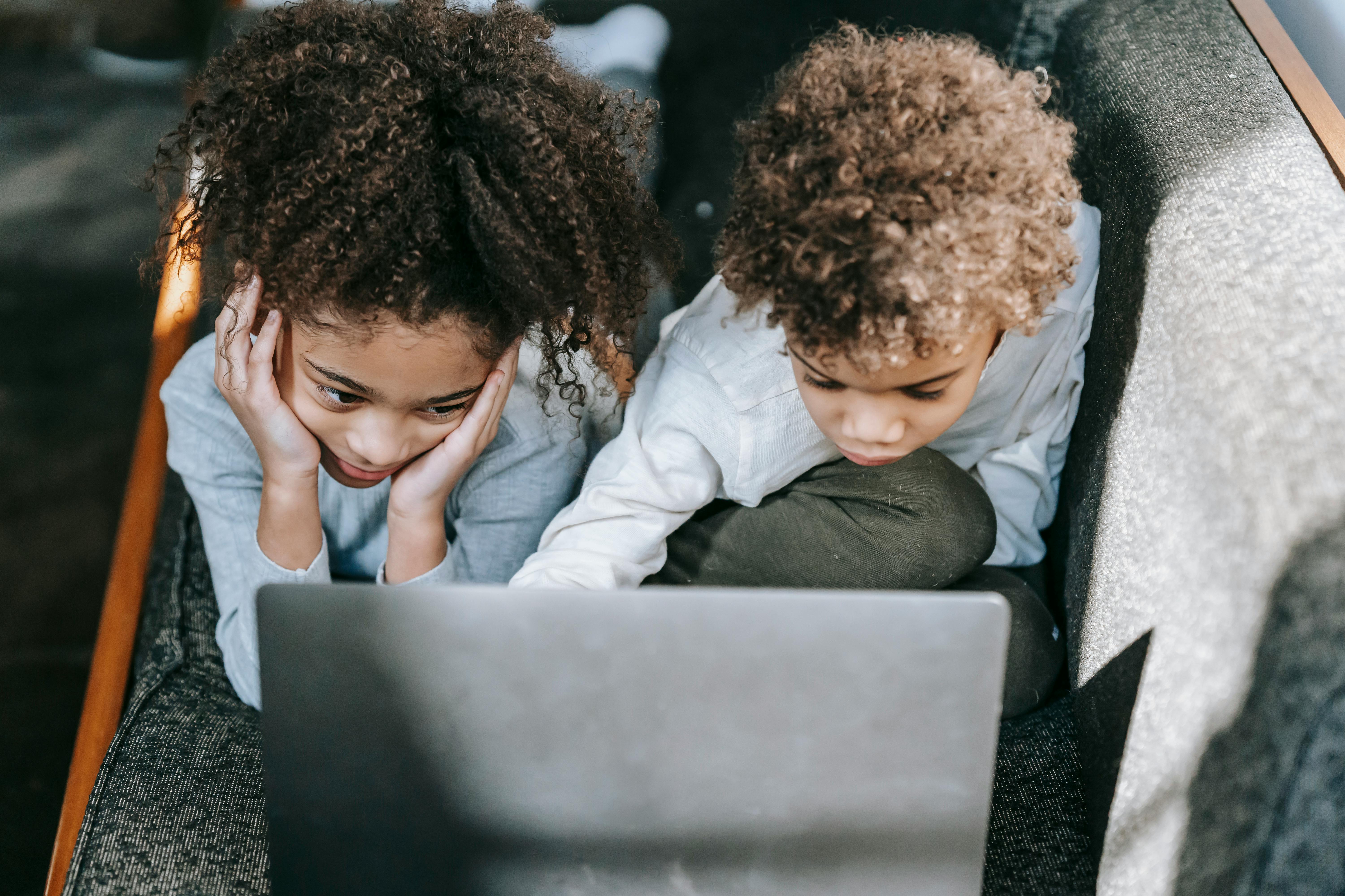 focused black children surfing laptop on sofa