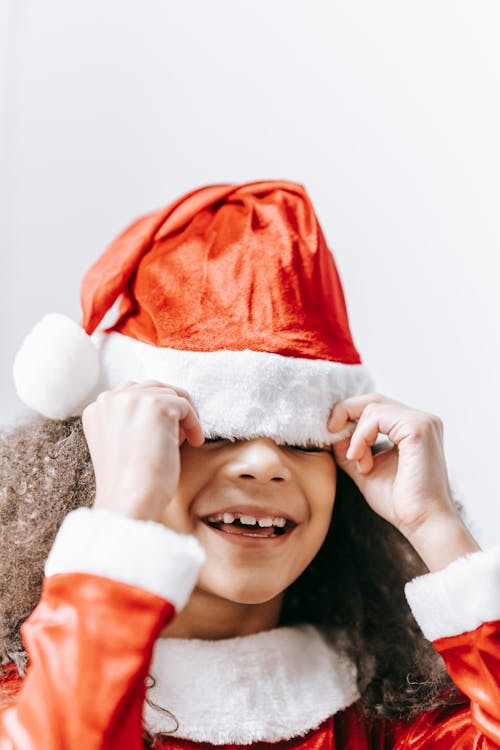 Free Smiling African American child in red Santa hat with pompon celebrating New Year holiday Stock Photo