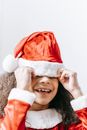 Smiling African American child in red Santa hat with pompon celebrating New Year holiday