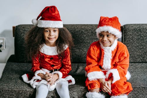 Content black children in Santa costumes resting on sofa