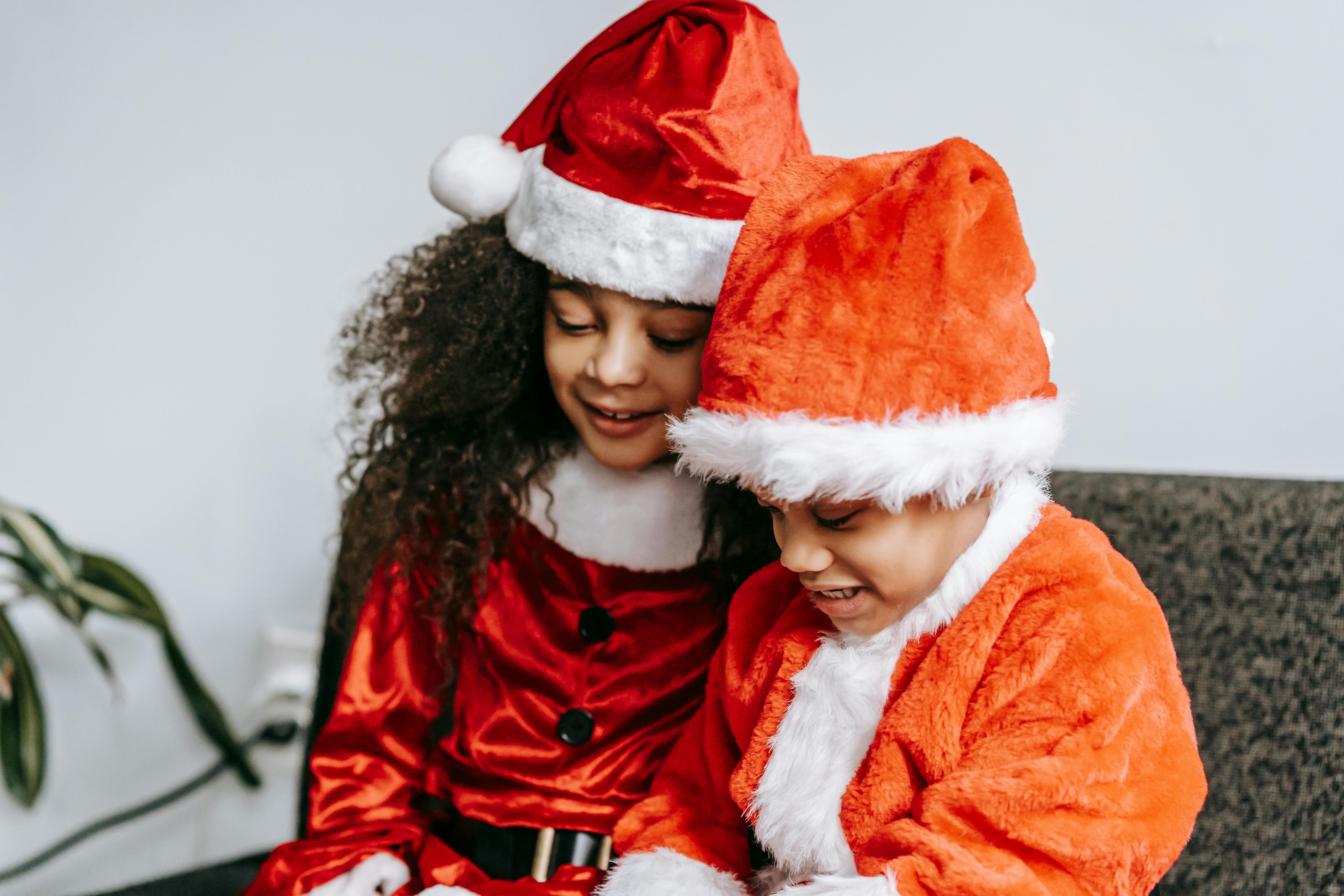 adorable black children in santa costumes sitting on sofa