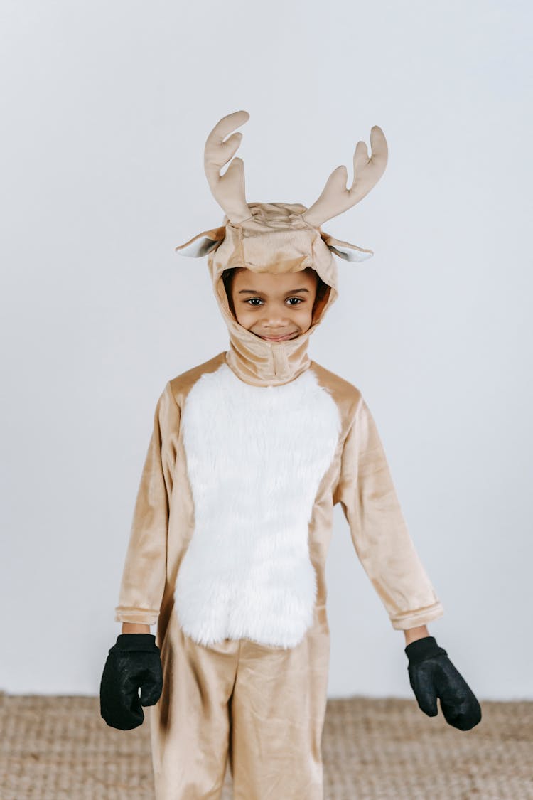 Cute Black Boy In Deer Costume Standing In Studio