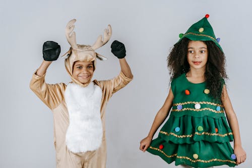 Cheerful black kids in Christmas costumes playing in studio