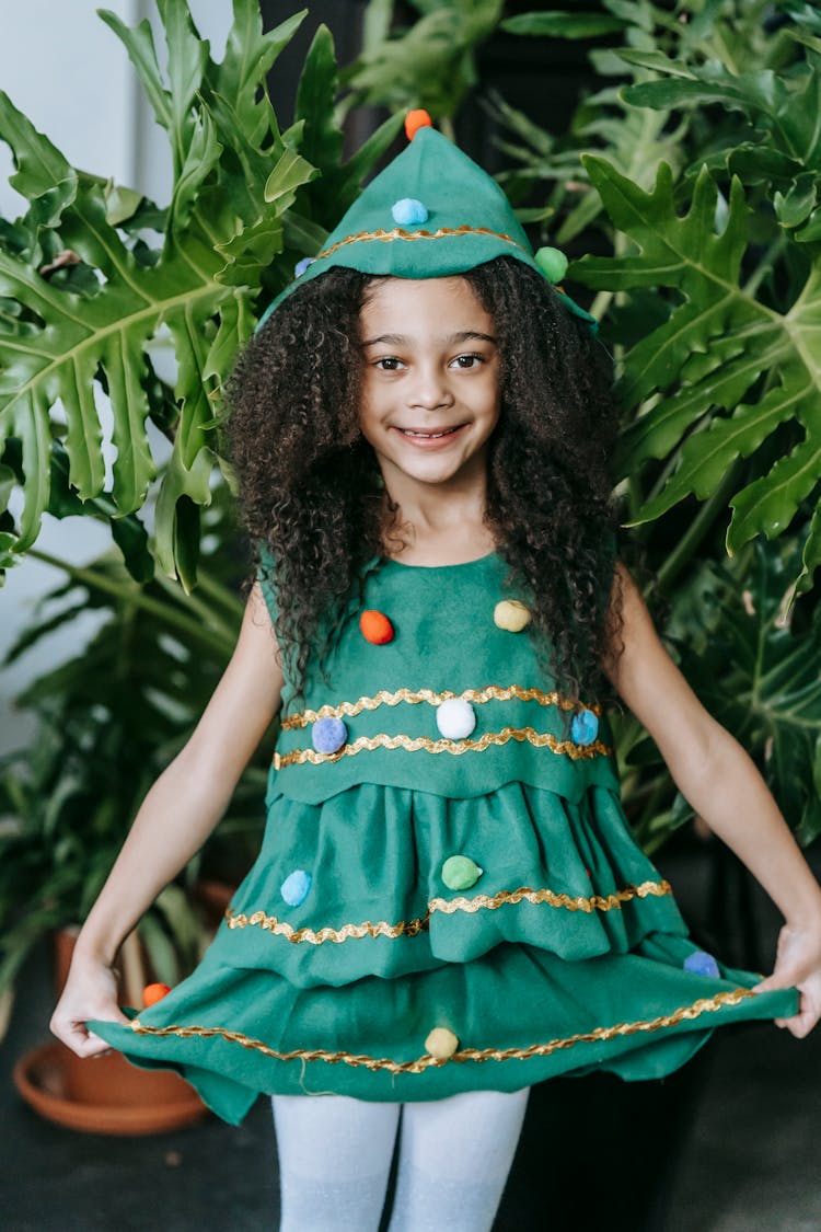 Happy Black Girl In Christmas Tree Costume Near Potted Plant