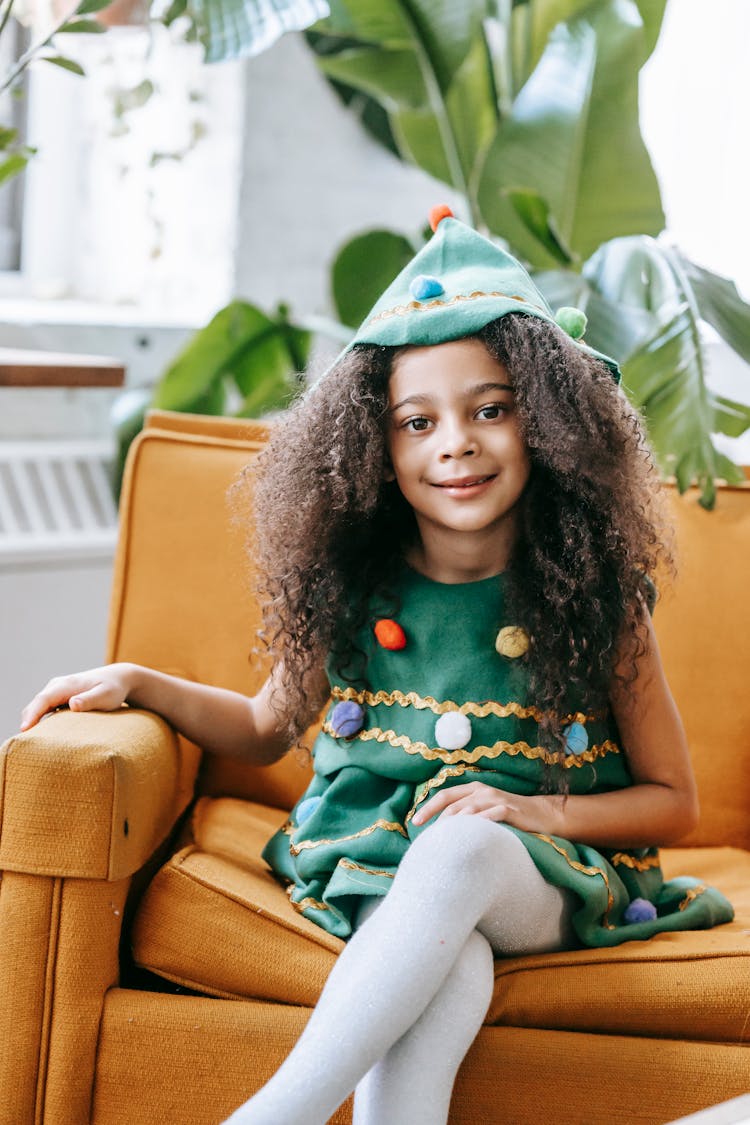 Cute Black Girl In Christmas Tree Costume Sitting On Armchair