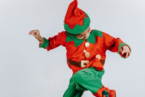 Free Happy African American boy wearing colorful elf outfit and headwear having fun while standing on white background during Christmas holiday Stock Photo