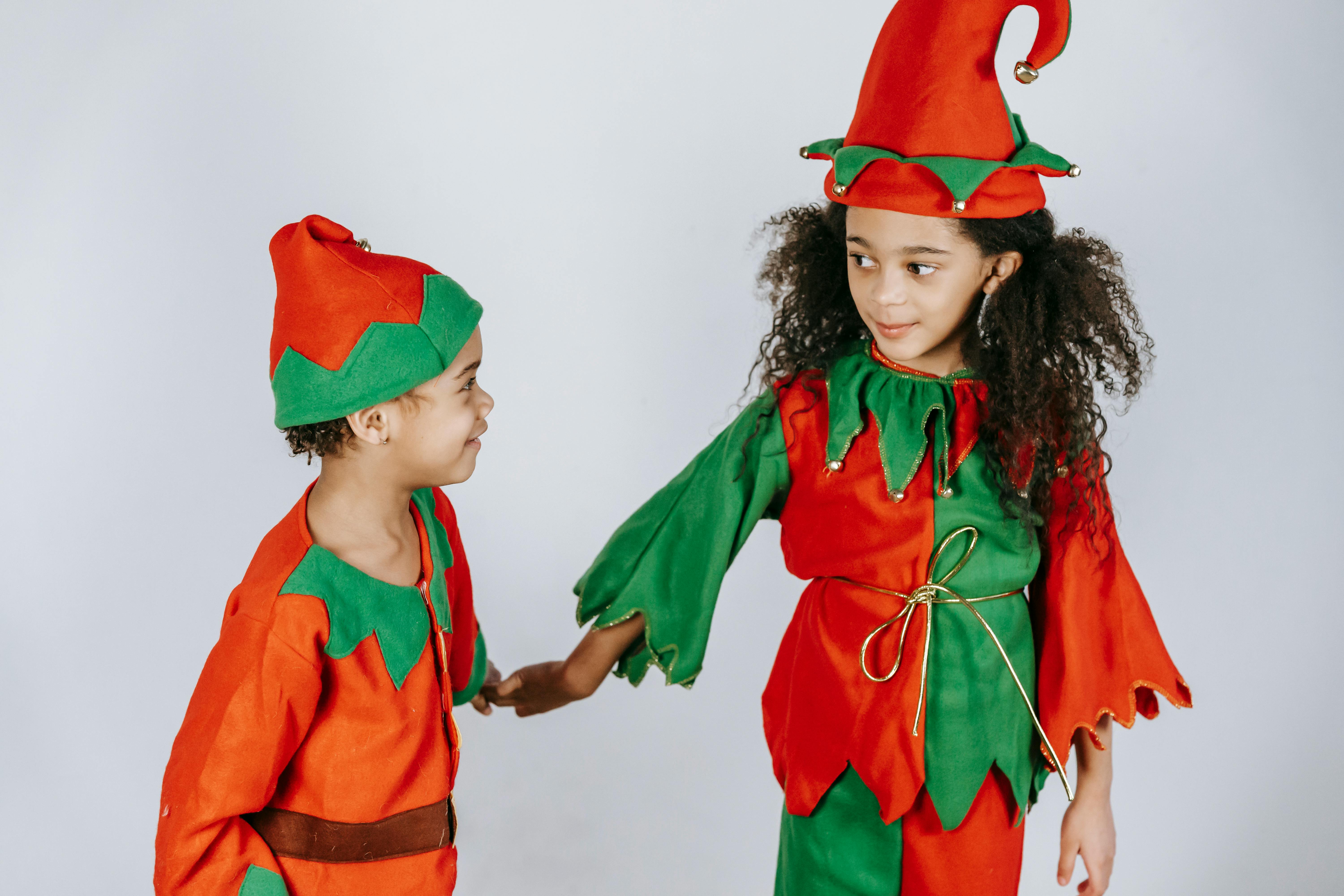 Two joyful children in elf costumes celebrating the holiday season together.